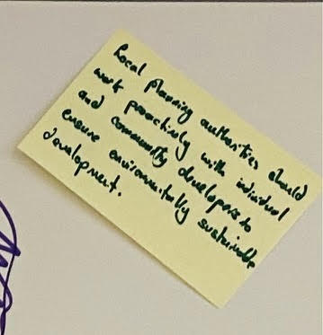 A single sticky note with writing on stuck to a wall