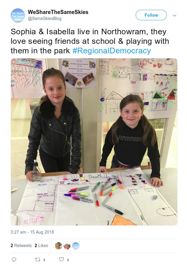 Screenshot of a Twitter post showing two girls in Huddersfield market standing with their hand drawn maps of their neighbourhood